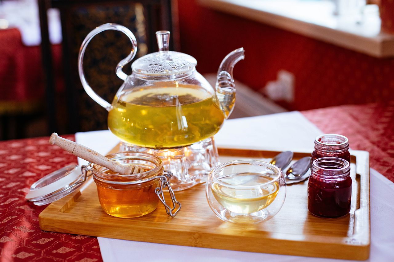 Image of a teapot with honey and two glasses of tea.