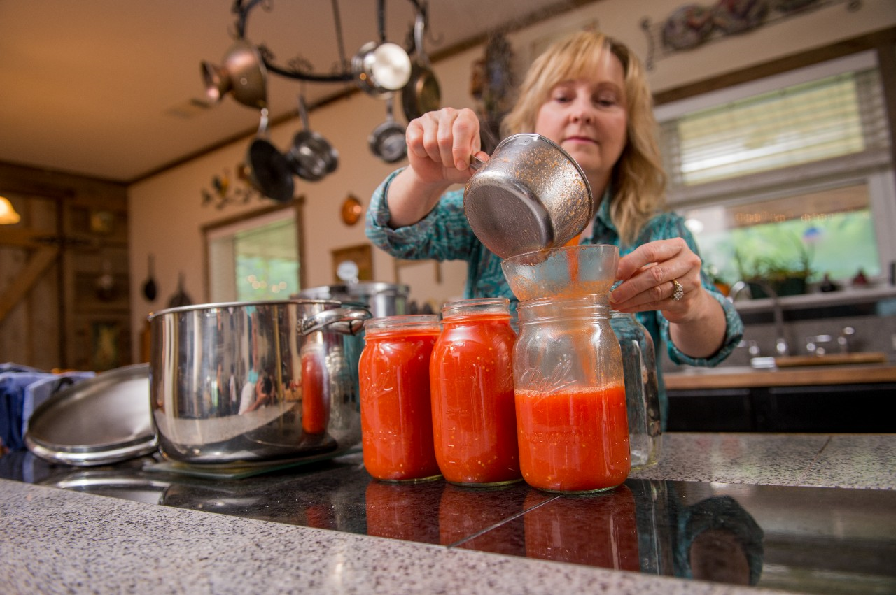 Image of a person getting canning jars ready for pressure canner.