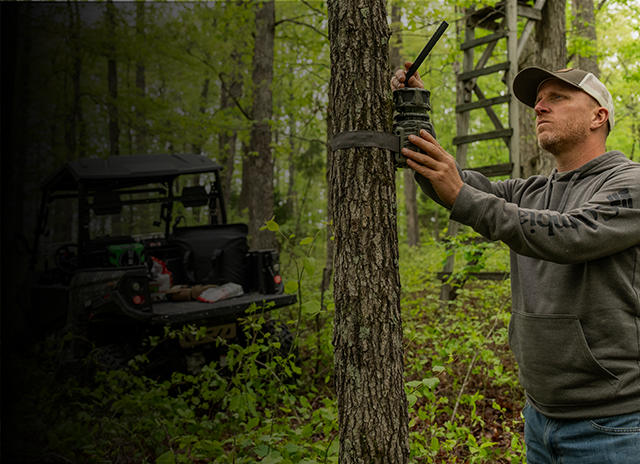 Man setting up a trail camera outside