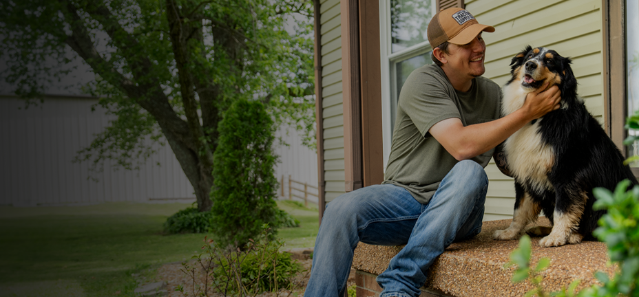 A man petting a happy dog on a porch. New year, new ways to boost their well-being. Shop pet supplements and vitamins.