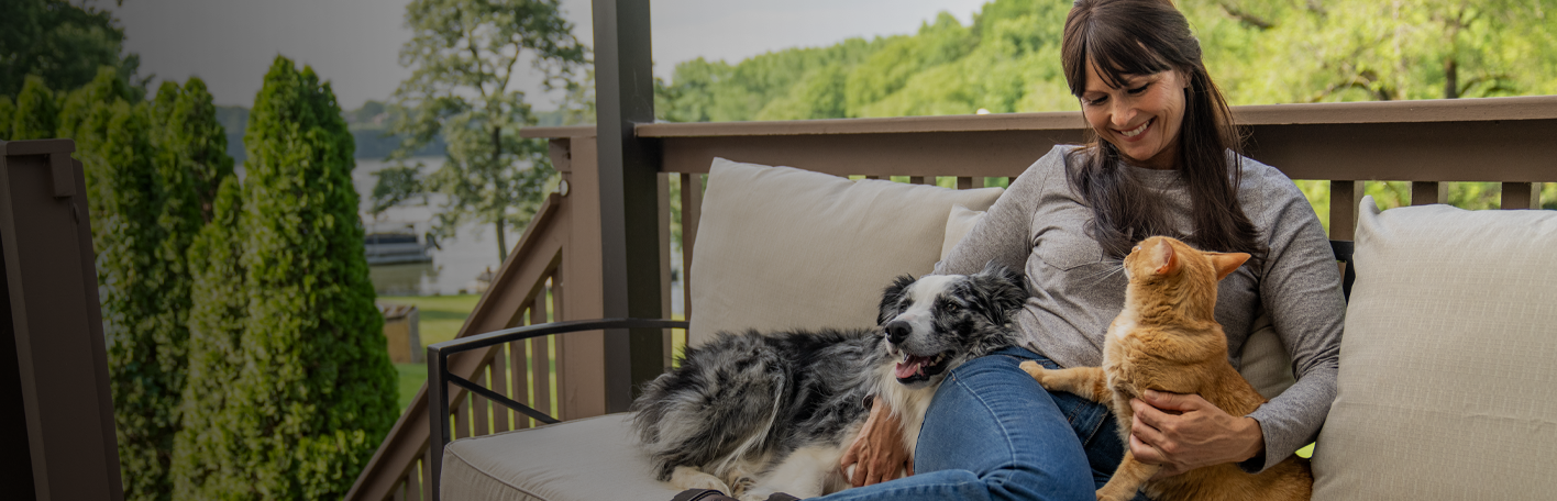Just in for pets banner with text, Fetch something new for them to love, featuring a woman sitting outside with a dog and cat. Shop now. 