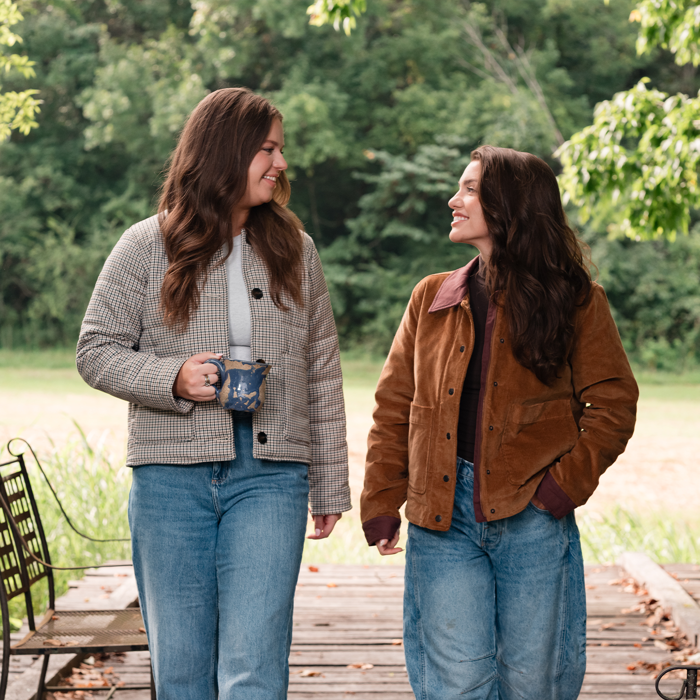 Two women wearing fall jackets and jeans are shown walking outdoors. See items.
