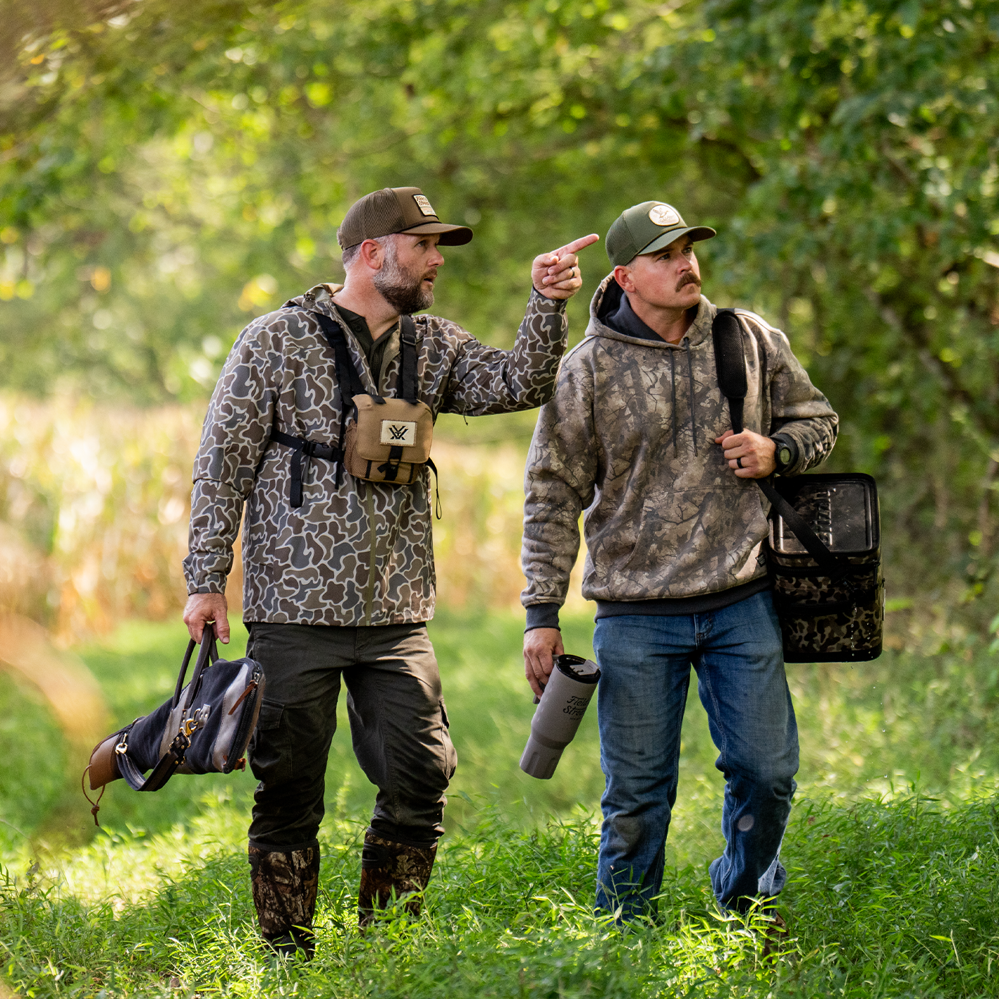 Two men wearing camouflage jackets and caps are shown walking outdoors. See items.