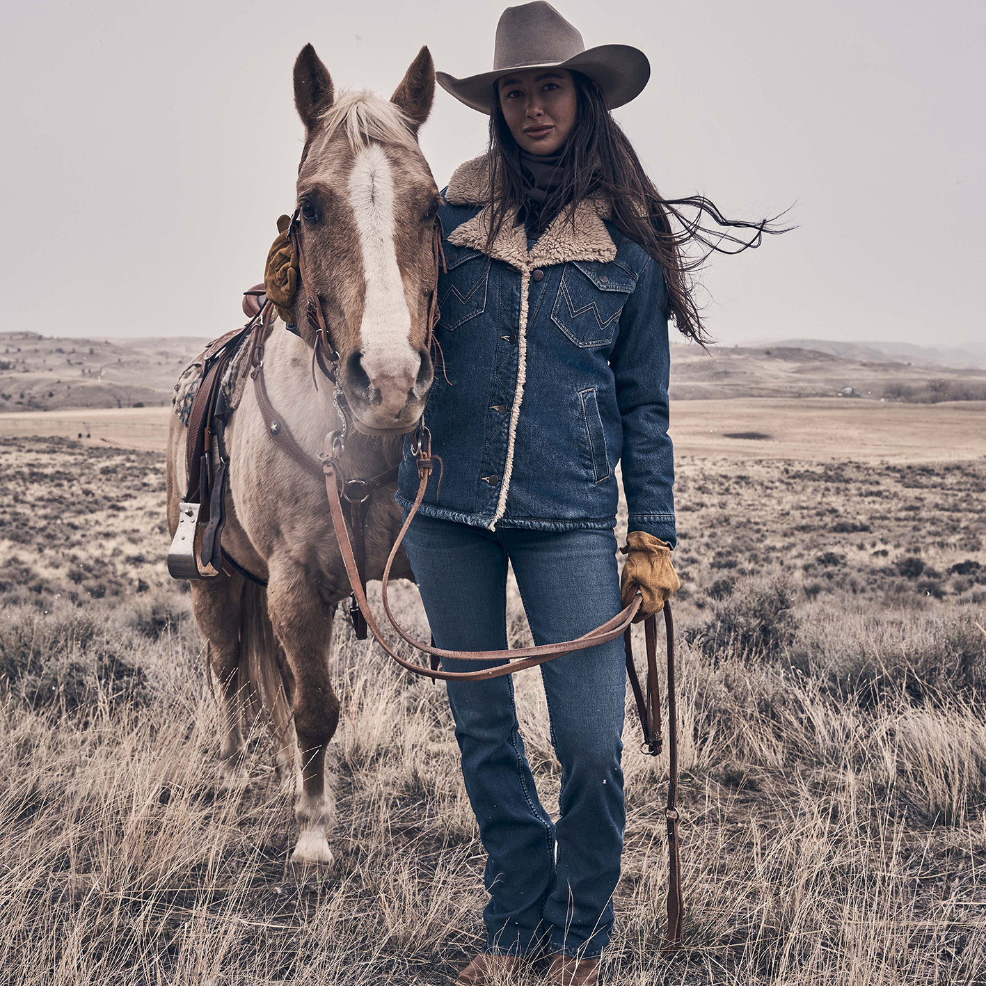 Woman with horse in a field wearing sherpa lined denim coat