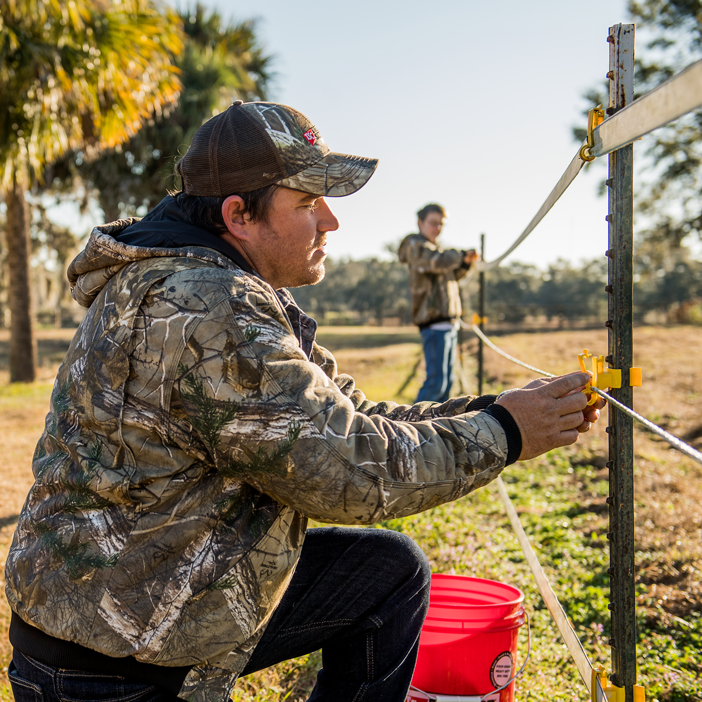 A man using polytape, polyrope, t-post clips and t-posts.