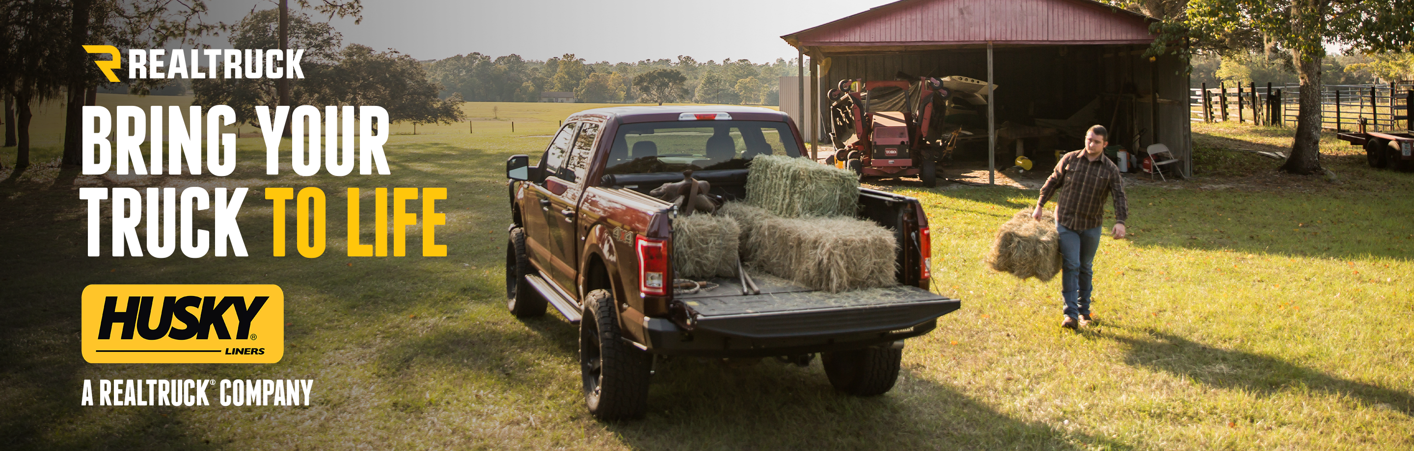  A banner with a sunny outdoor scene with a man carrying a load of hay to a truck with the text, realtruck, bring your truck to life.     