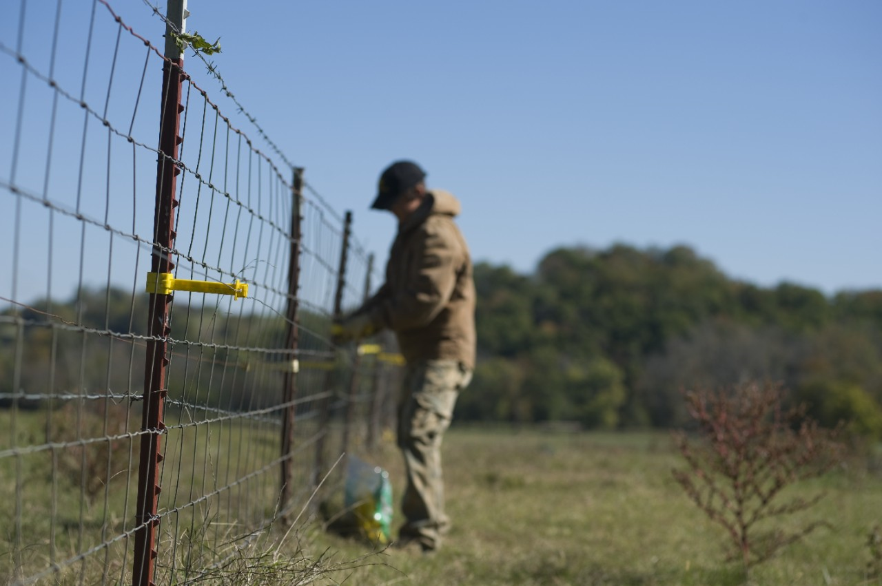 Image of a person working on an electric fence.