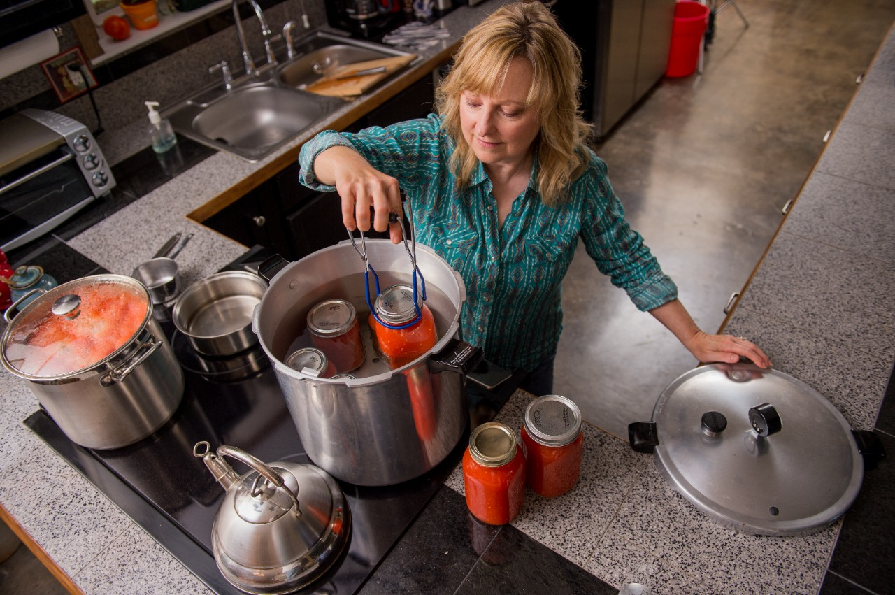 Image of a person in a kitchen water bath canning.