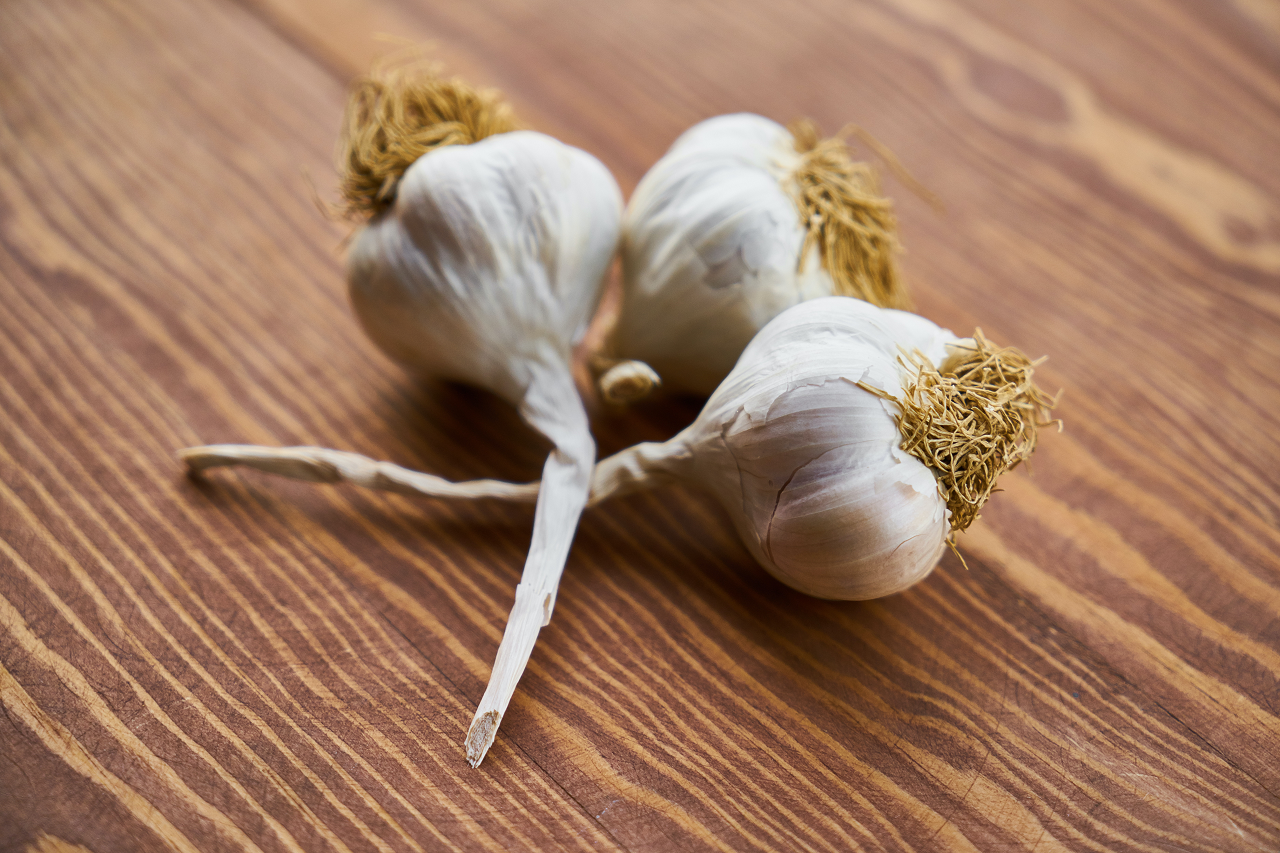 Image of longneck garlic on a wood table.