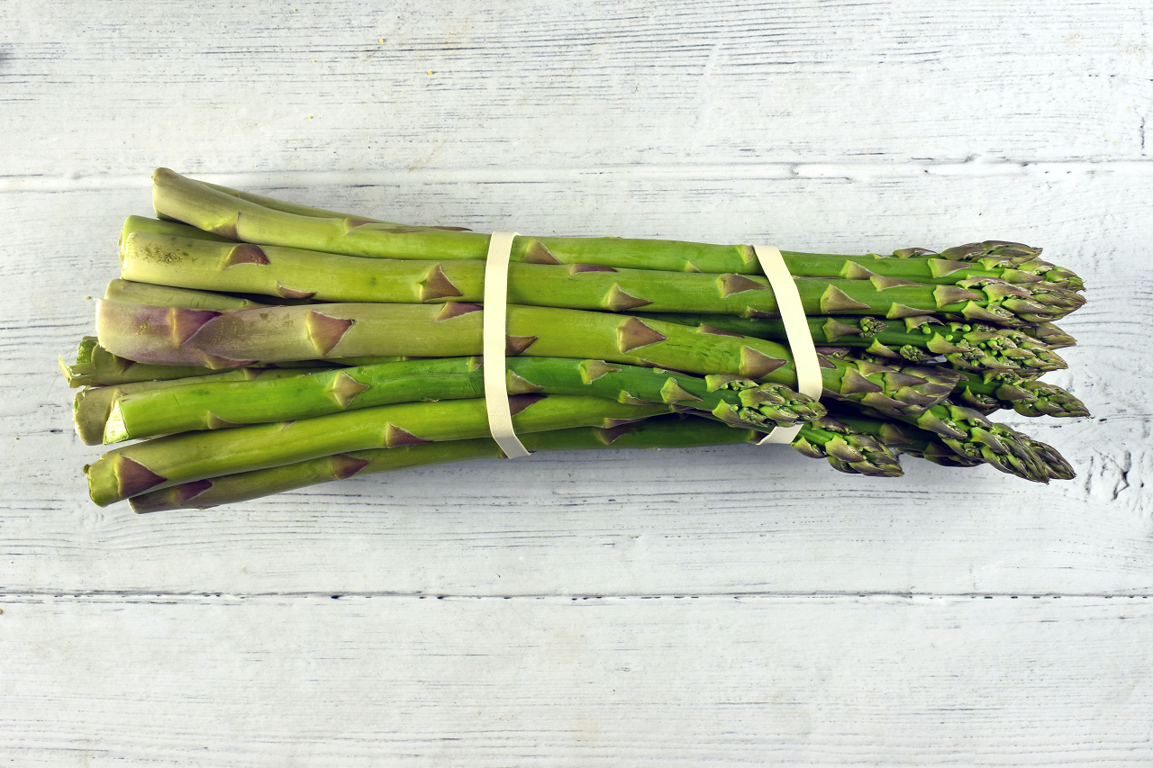 Image of an asparagus bunch on a wooden table.