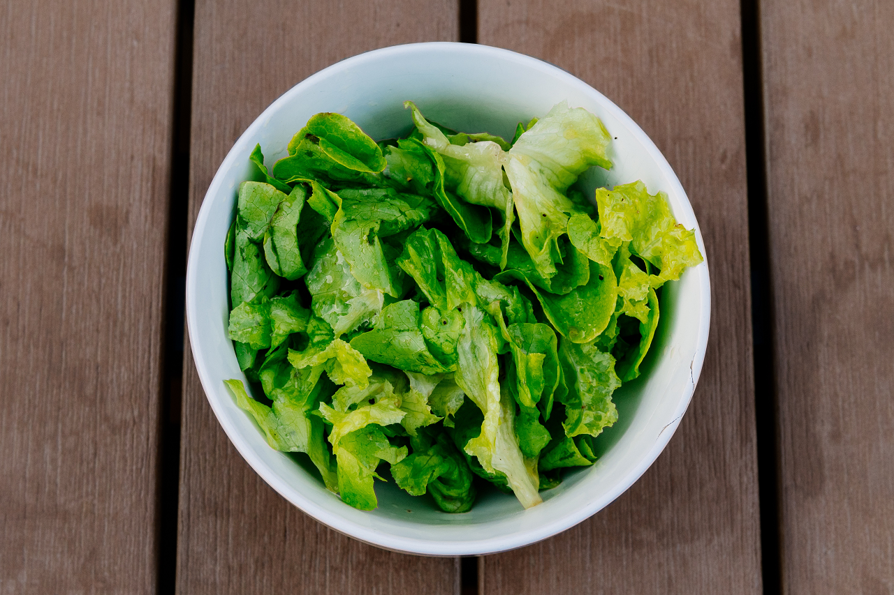 Image of chopped romain lettuce in a bowl on a wooden table.