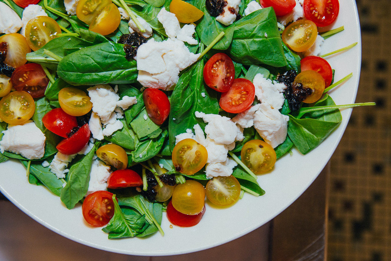 Image of spinach salad with cherry tomatoes and cheese.