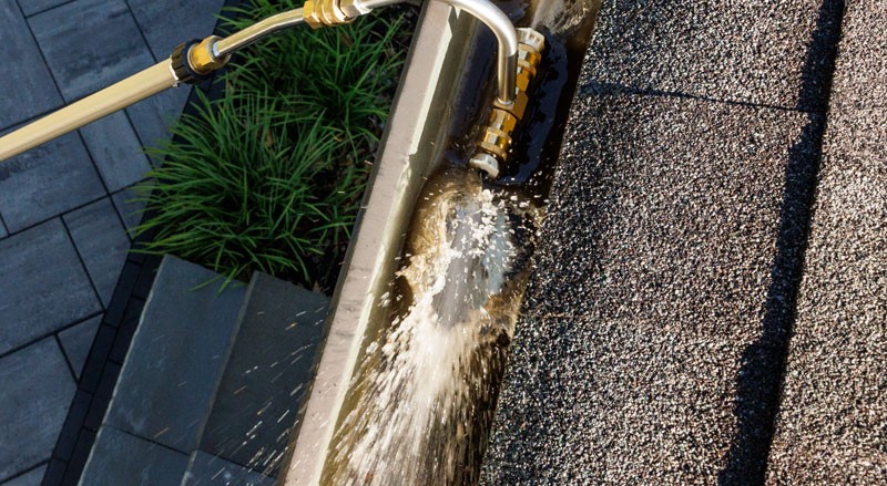 Power washer tool cleaning gutters with blasts of water