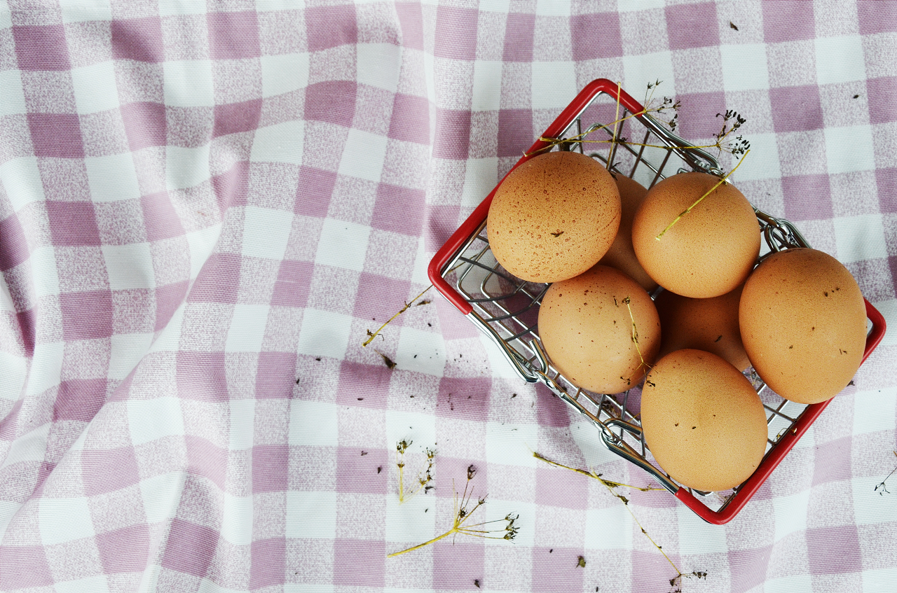 Image of eggs in a basket on a checkered table cloth.