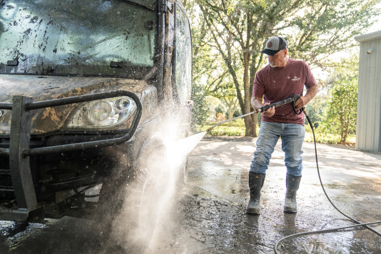 Image of a person using a power washer to clean an ATV.